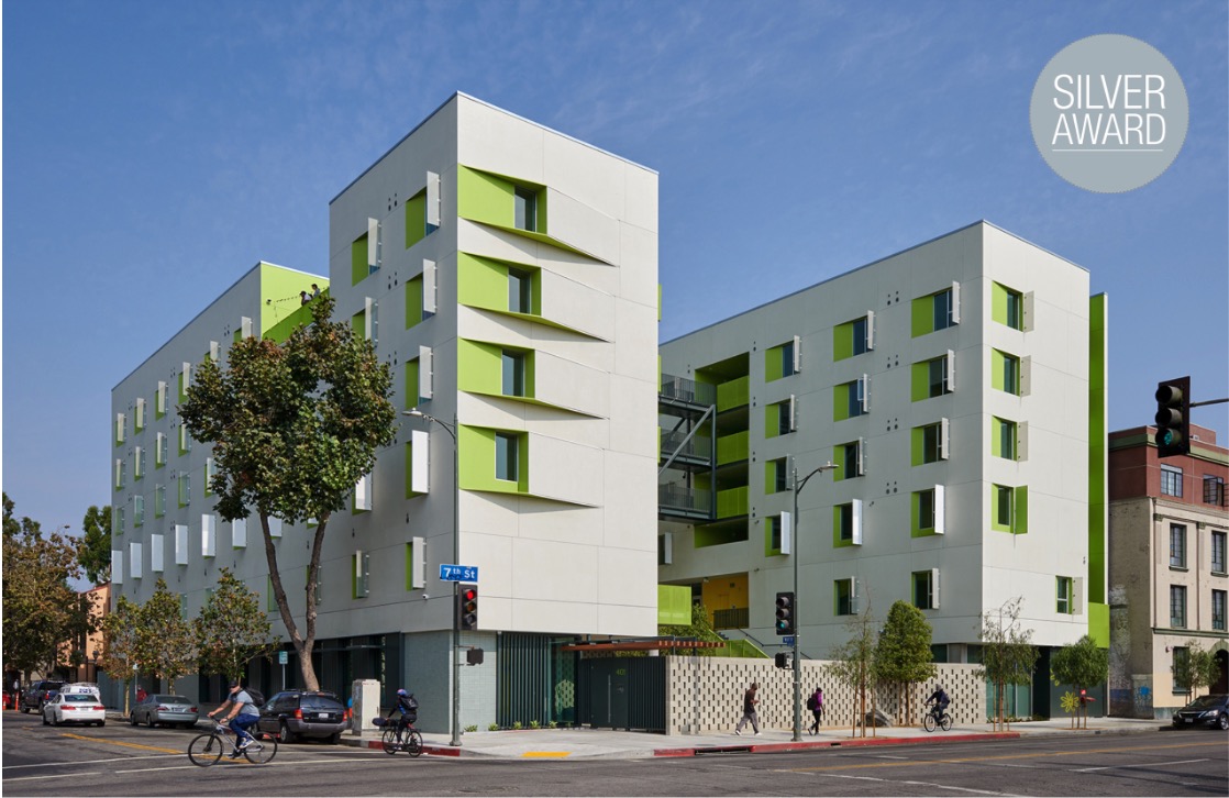 Modern apartment building with green accents on a city corner, awarded a silver award.