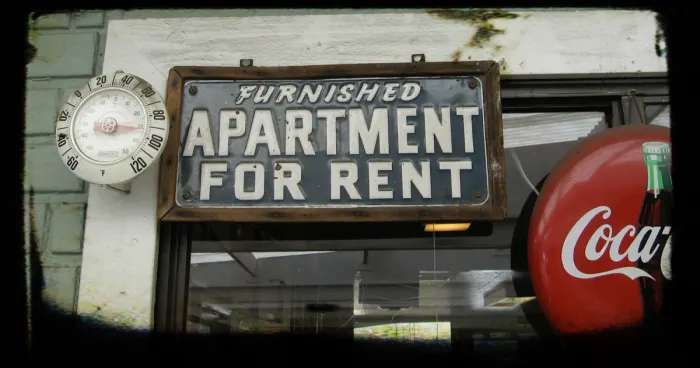 Vintage sign reading ‘Furnished Apartment For Rent’ next to a Coca-Cola sign.