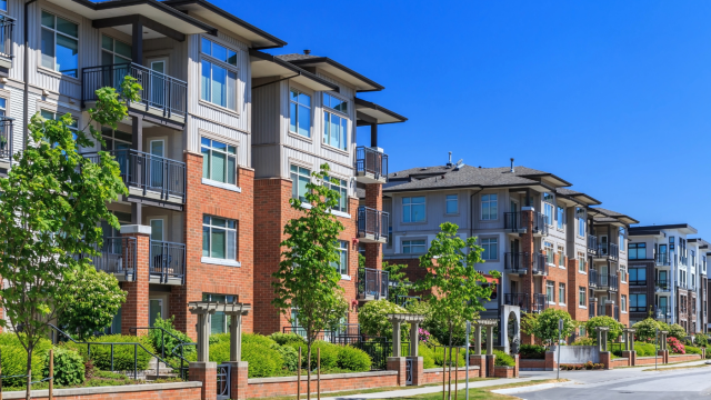 Modern apartment buildings with balconies and greenery along a quiet street